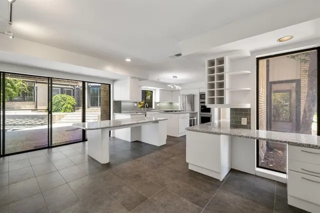 a large white kitchen with kitchen island a large window a sink and a counter top space