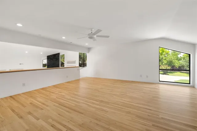 a view of an empty room with a window and a kitchen