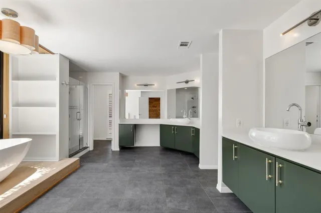 a large bathroom with a double vanity sink a large mirror and a bathtub