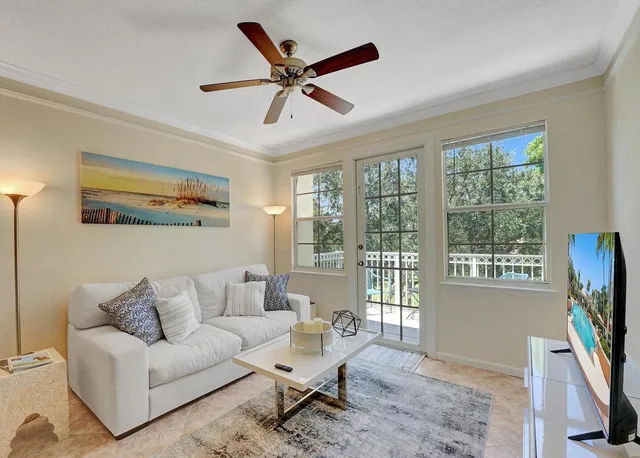 a living room with furniture a ceiling fan a flat screen tv and a large window