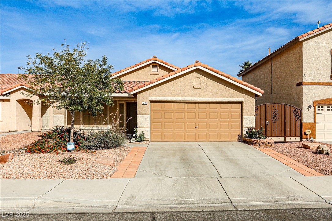 5128 Fall Meadows Avenue Las Vegas, NV 89130 - Photo 1 of 34 Mediterranean / spanish house with stucco siding, a gate, concrete driveway, a tiled roof, and an attached garage