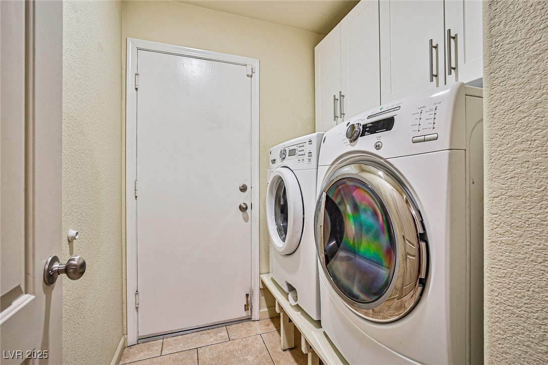 5128 Fall Meadows Avenue Las Vegas, NV 89130 - Photo 18 of 34 Laundry room with light tile patterned floors, separate washer and dryer, cabinet space, and a textured wall