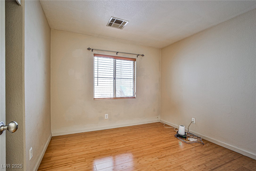 5128 Fall Meadows Avenue Las Vegas, NV 89130 - Photo 19 of 34 Unfurnished room with light wood-style flooring, a textured wall, and a textured ceiling
