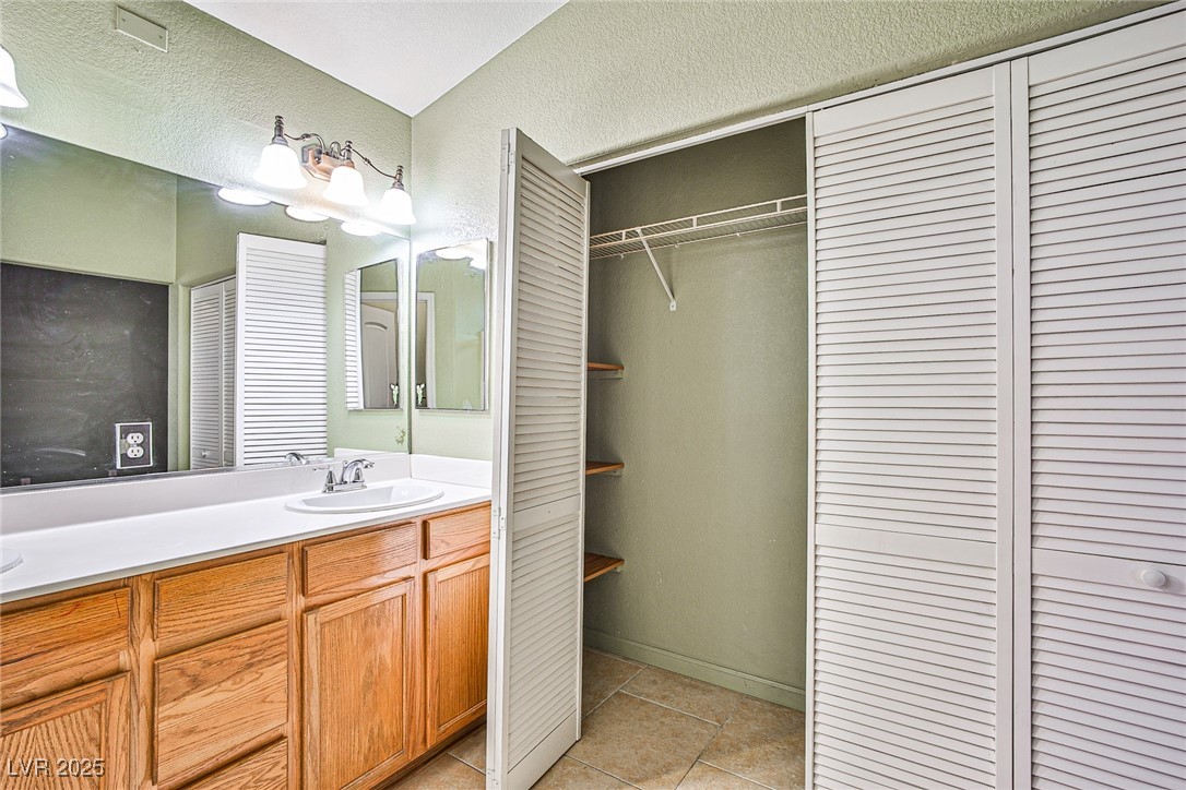 5128 Fall Meadows Avenue Las Vegas, NV 89130 - Photo 29 of 34 Full bathroom with vanity, light tile patterned flooring, and a textured wall
