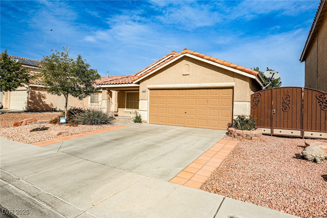 5128 Fall Meadows Avenue Las Vegas, NV 89130 - Photo 3 of 34 View of front of home with a gate, stucco siding, concrete driveway, an attached garage, and a tile roof