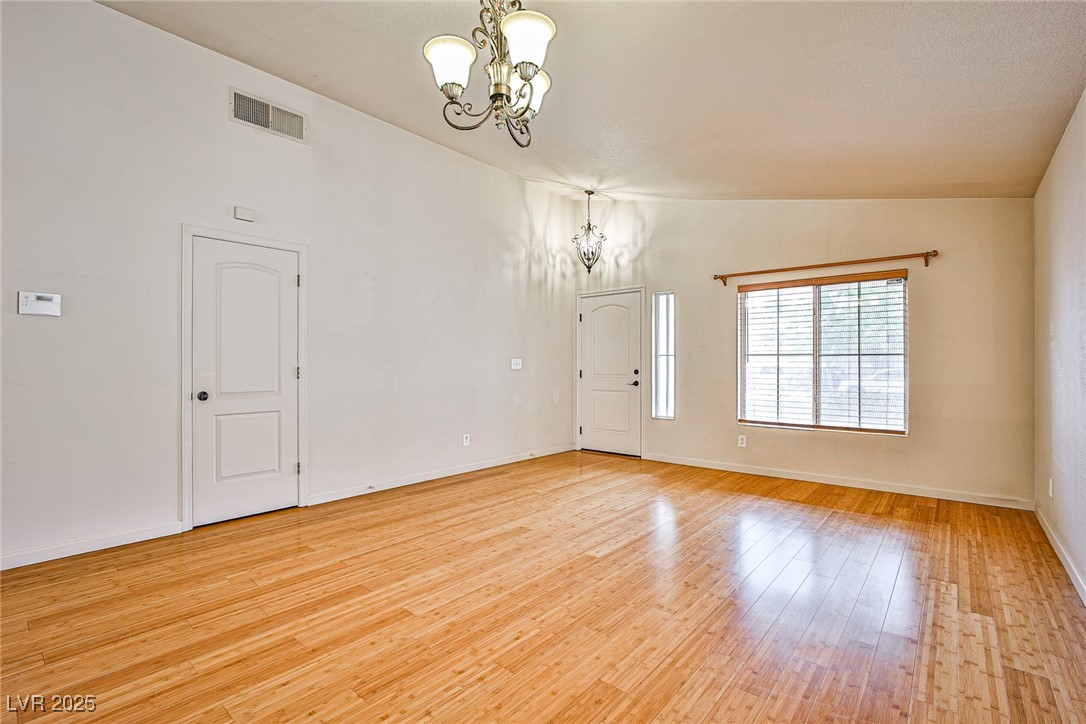 5128 Fall Meadows Avenue Las Vegas, NV 89130 - Photo 6 of 34 Empty room featuring a chandelier, vaulted ceiling, and light wood-type flooring
