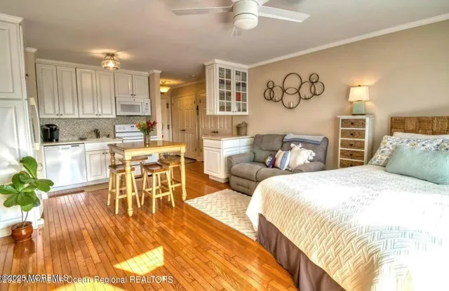 a spacious bedroom with a bed a table and potted plants with wooden floor