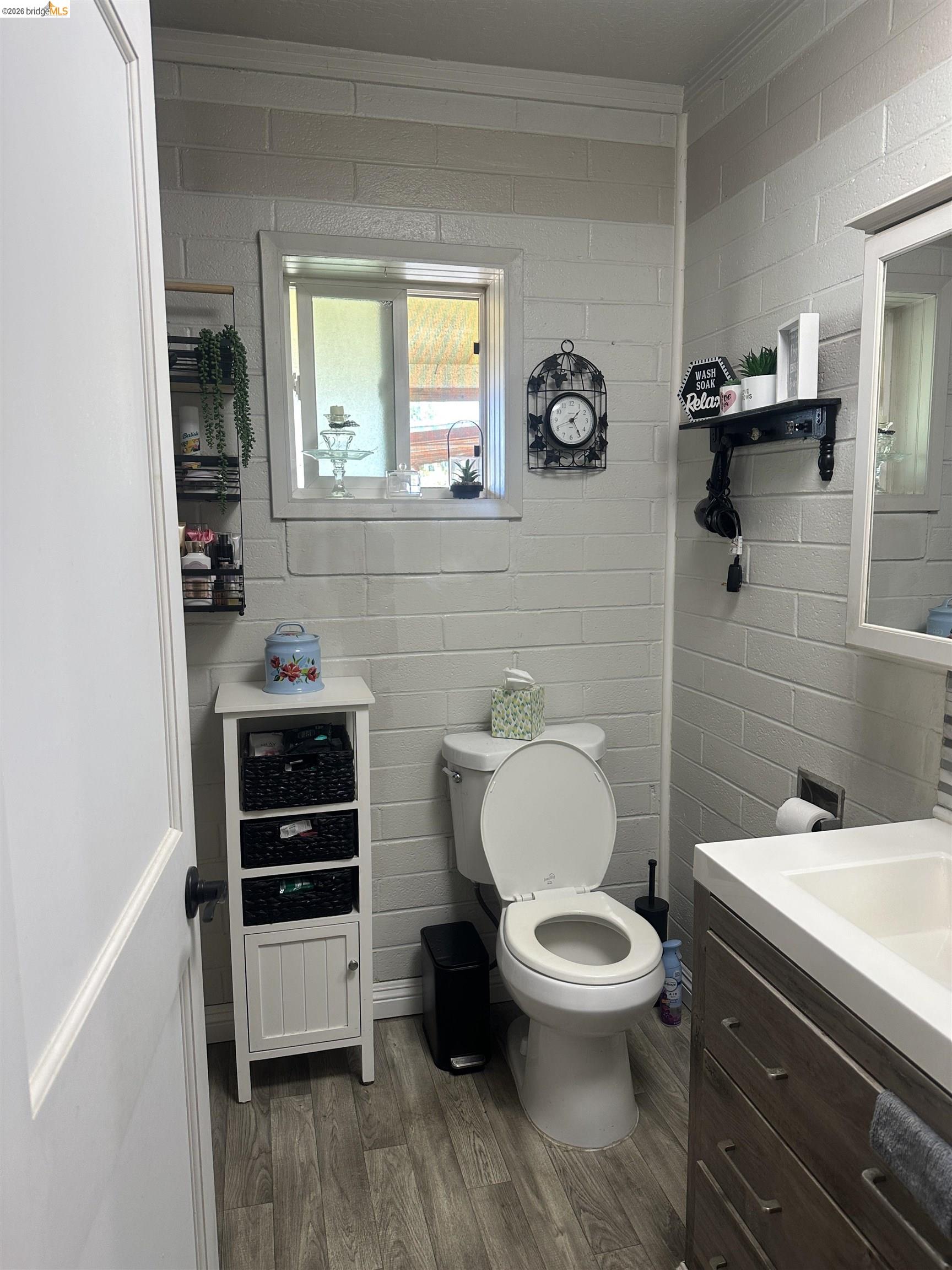 2831 Fabian Road Tracy, CA 95377 - Photo 16 of 23 Wood-finish flooring, white brick-patterned walls, built-in window, vanity with integrated sink, and white storage cabinet