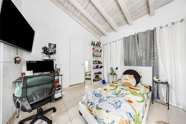 a bedroom that has a bed and a flat tv screen on the dresser
