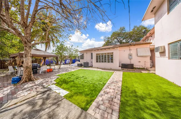 a view of a house with backyard and a tree