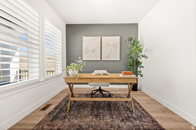 14728 South Canyon Pointe Road Draper, UT 84020 - Photo 5 of 35 Bright room featuring two large windows with white louvered shutters, light wood-finish flooring, and a contrasting accent wall