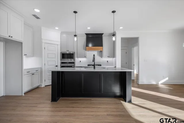 a kitchen with stainless steel appliances granite countertop a refrigerator oven a sink dishwasher and white cabinets with wooden floor