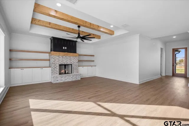 a view of an empty room with wooden floor fireplace and a window