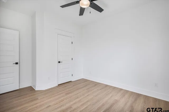 an empty room with wooden floor and ceiling fan