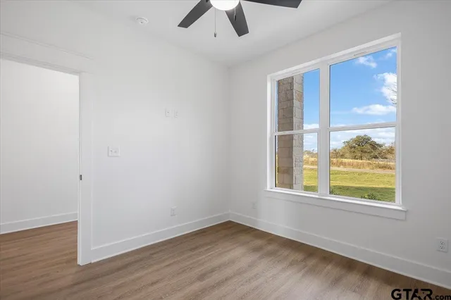 an empty room with a ceiling fan and wooden floor