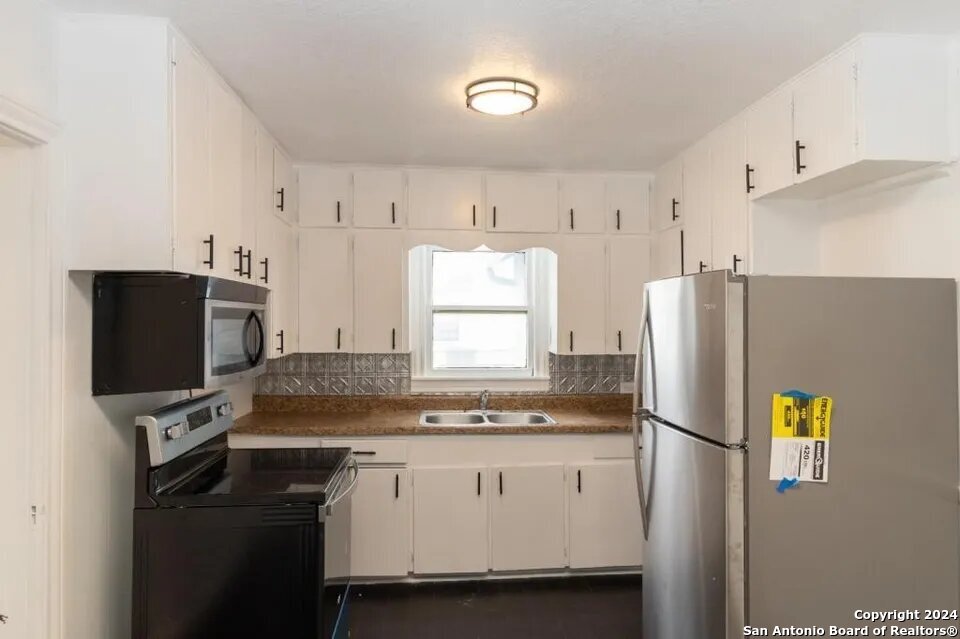 719 Kelly Street Poteet, TX 78065 - Photo 5 of 12 a kitchen with stainless steel appliances a refrigerator a stove a microwave and a refrigerator