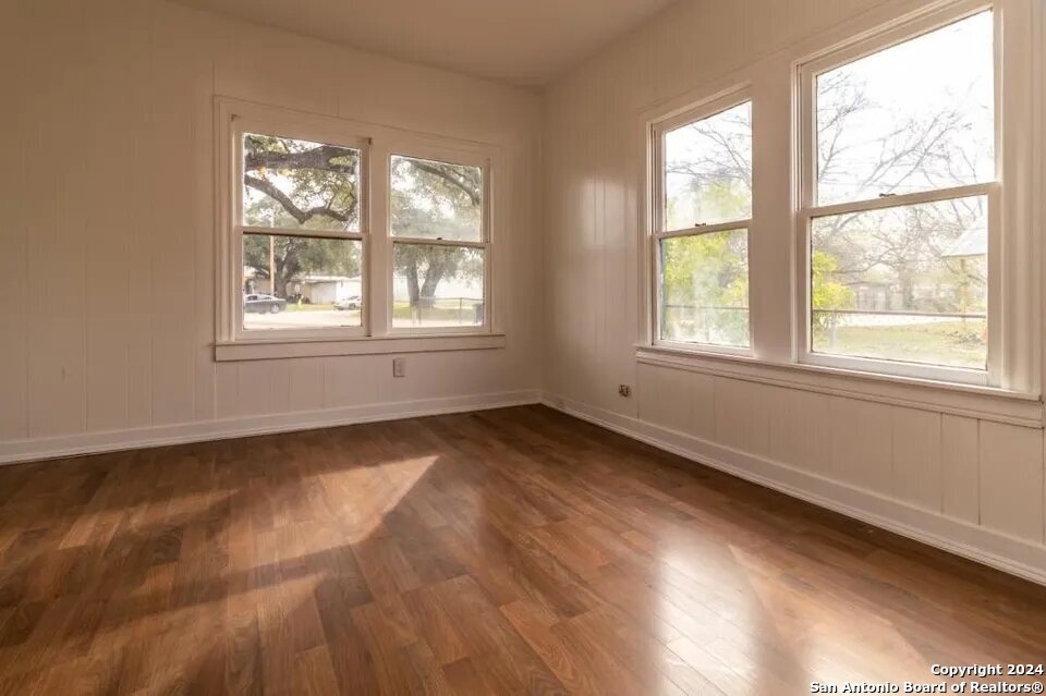 719 Kelly Street Poteet, TX 78065 - Photo 7 of 12 an empty room with wooden floor and windows
