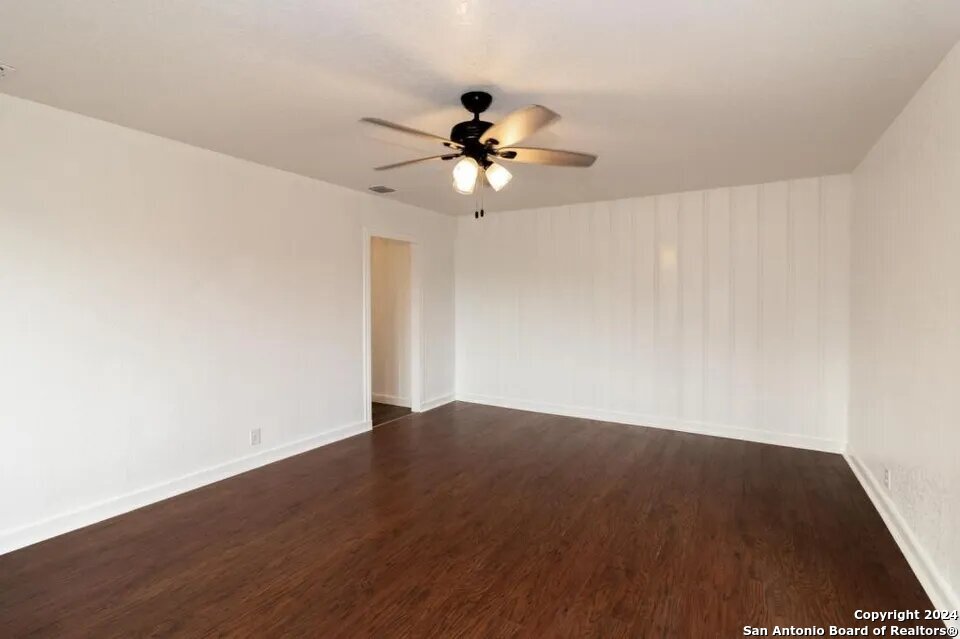 719 Kelly Street Poteet, TX 78065 - Photo 10 of 12 an empty room with wooden floor ceiling fan and windows