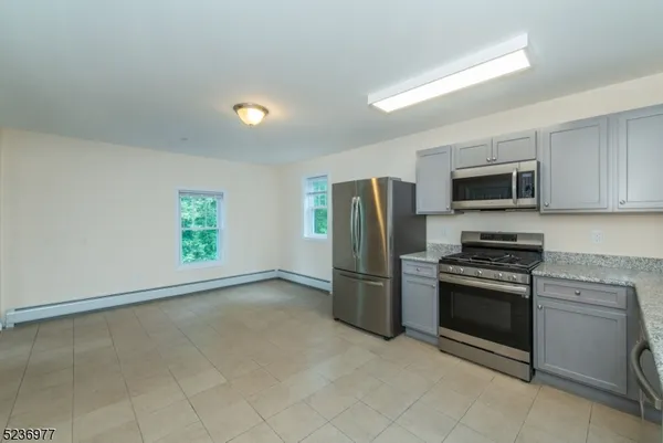 a kitchen with a stainless steel appliances granite countertop a refrigerator and a stove top oven