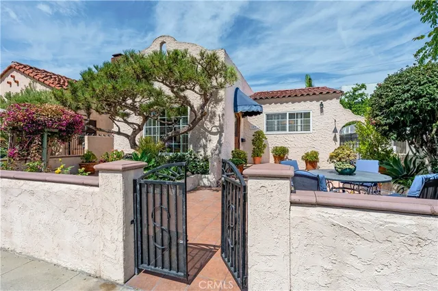 a view of a white house next to a yard with potted plants