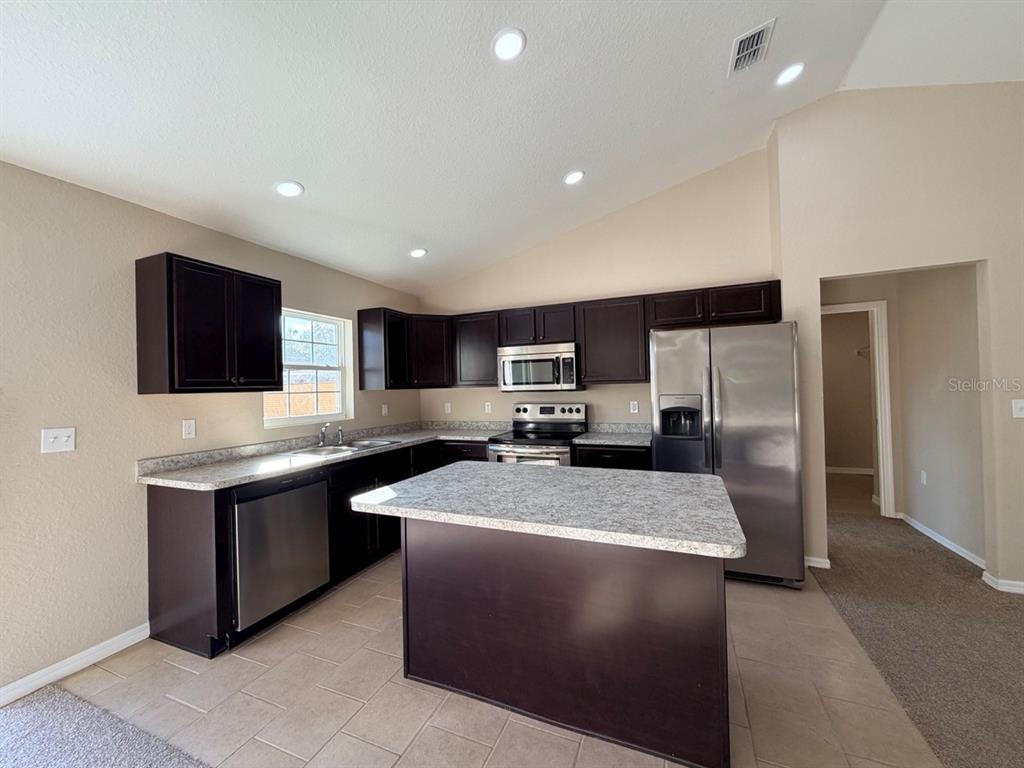14656 Southwest 21st Place Ocala, FL 34481 - Photo 14 of 52 a kitchen with stainless steel appliances granite countertop a sink stove and refrigerator