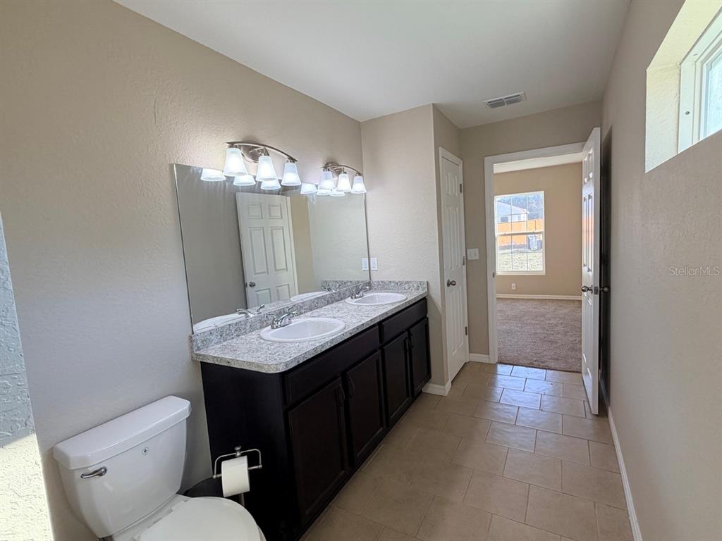 14656 Southwest 21st Place Ocala, FL 34481 - Photo 26 of 52 a bathroom with a granite countertop sink a toilet a mirror and vanity