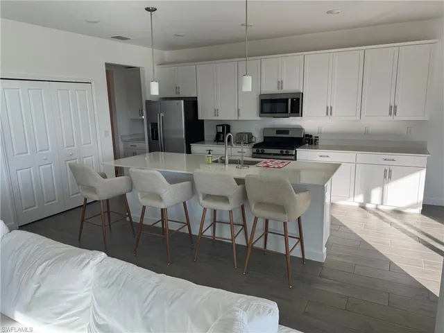 a kitchen with stainless steel appliances a dining table chairs microwave and sink