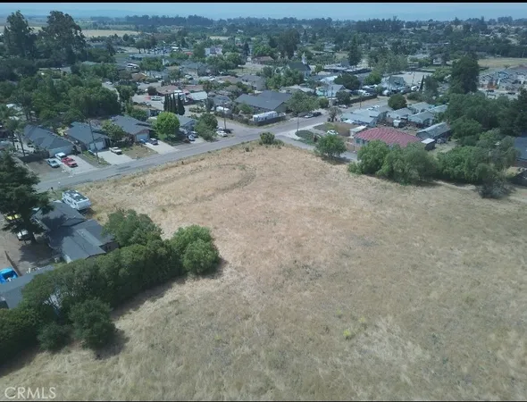 an aerial view of residential houses with outdoor space and trees