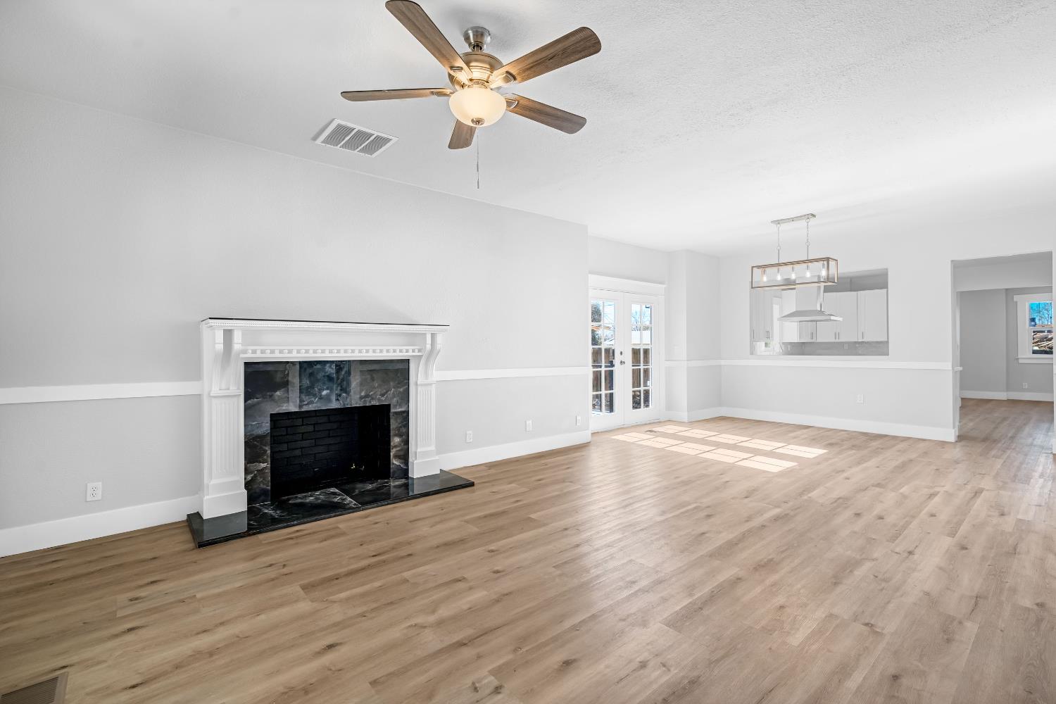 1249 D Street Reedley, CA 93654 - Photo 5 of 40 an empty room with windows fireplace and wooden floor