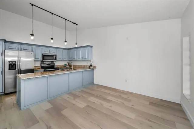 a kitchen with kitchen island granite countertop a sink cabinets and stainless steel appliances