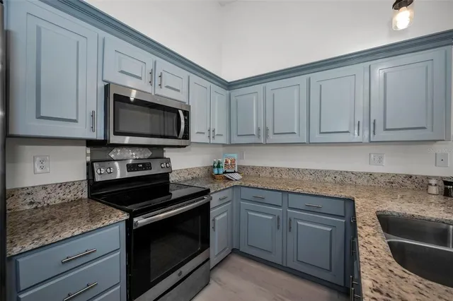 a kitchen with granite countertop white cabinets and a sink