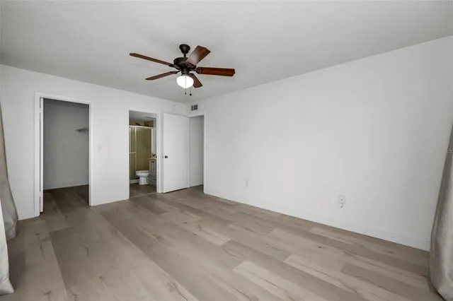 a view of empty room with wooden floor and fan