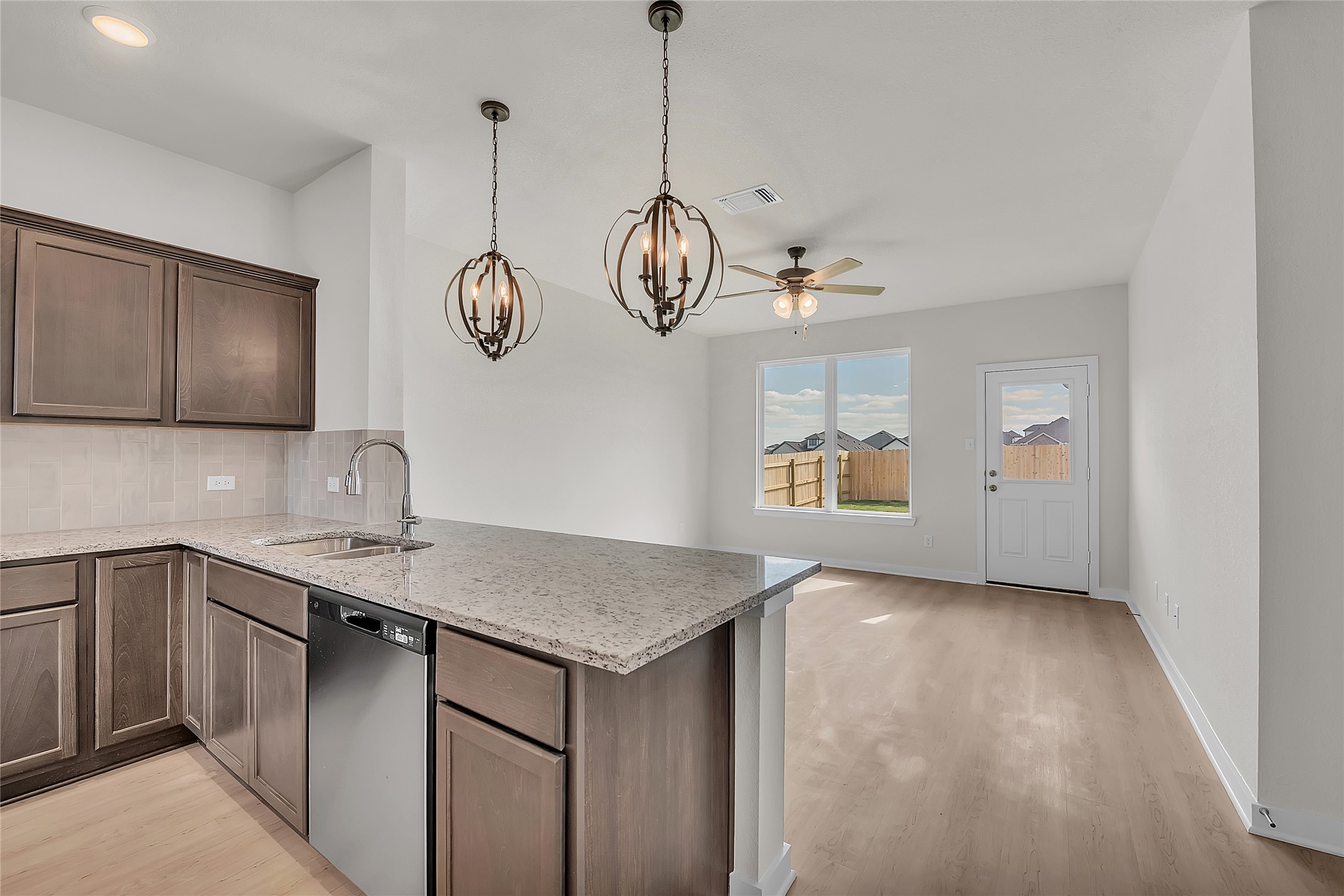 308 Boatright Boulevard Jarrell, TX 76537 - Photo 26 of 31 Kitchen with tasteful backsplash, stainless steel dishwasher, light stone countertops, and light wood finished floors