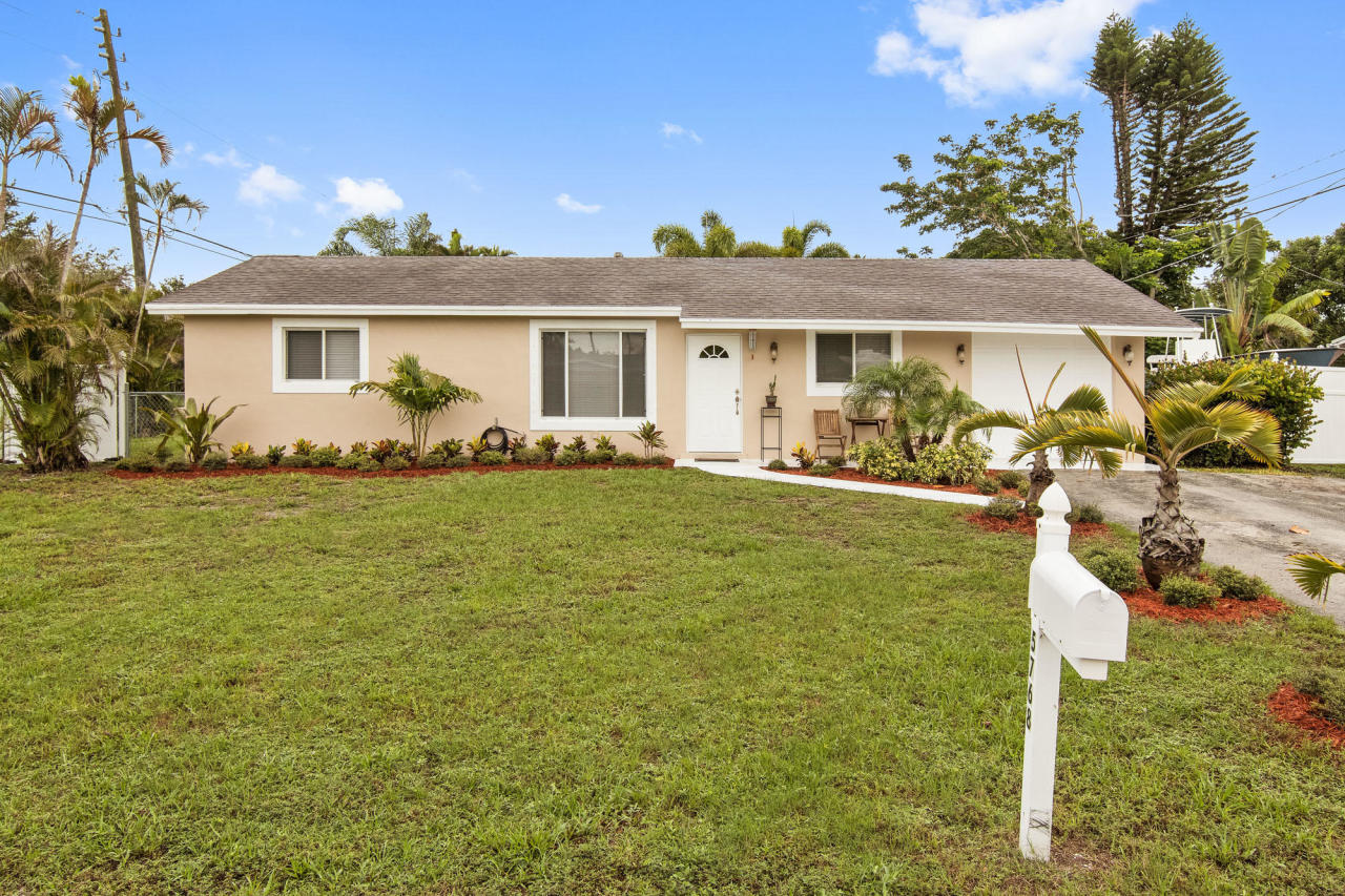 5768 Sullivan Road Jupiter, FL 33458 - Photo 2 of 18 a front view of a house with a garden and yard