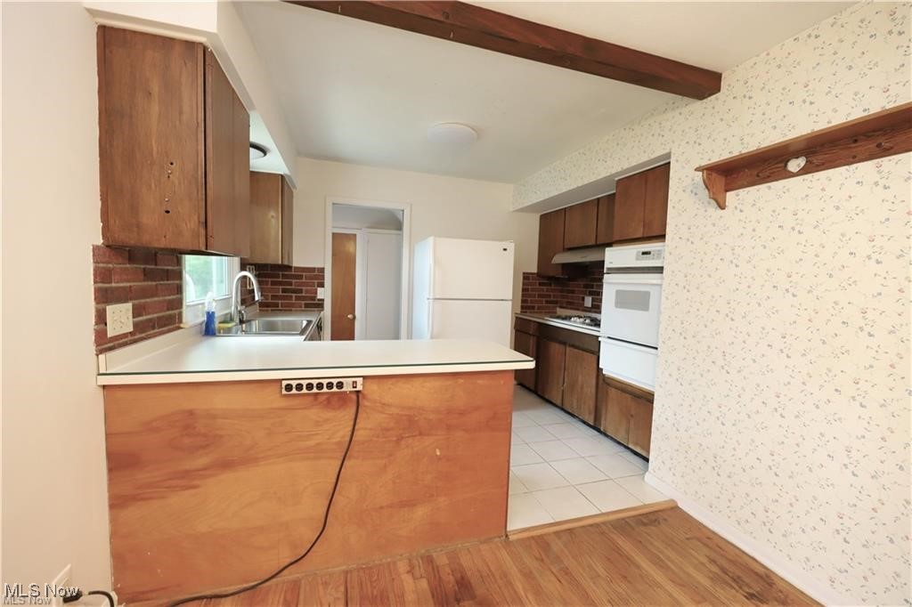 890 Wadsworth Road Medina, OH 44256 - Photo 4 of 22 Kitchen featuring light countertops, brown cabinets, light wood finished floors, decorative backsplash, and beamed ceiling