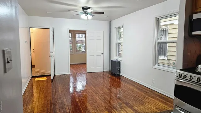 a view of an empty room with window and wooden floor