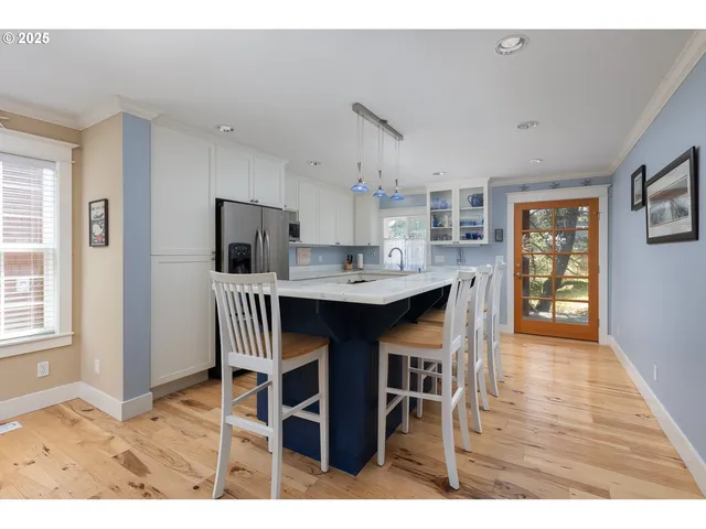 a dining room with stainless steel appliances kitchen island granite countertop a table chairs and a refrigerator
