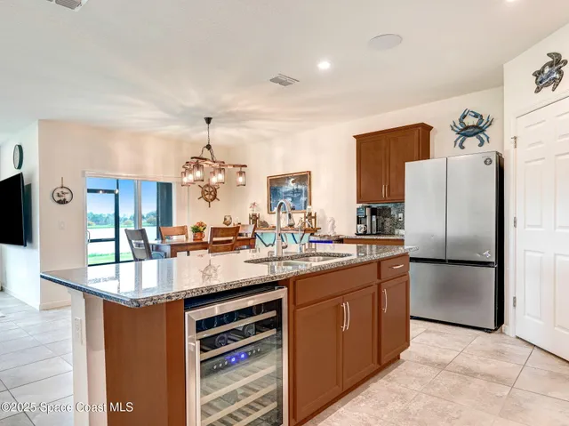 a kitchen with stainless steel appliances kitchen island granite countertop a dining table chairs and a refrigerator