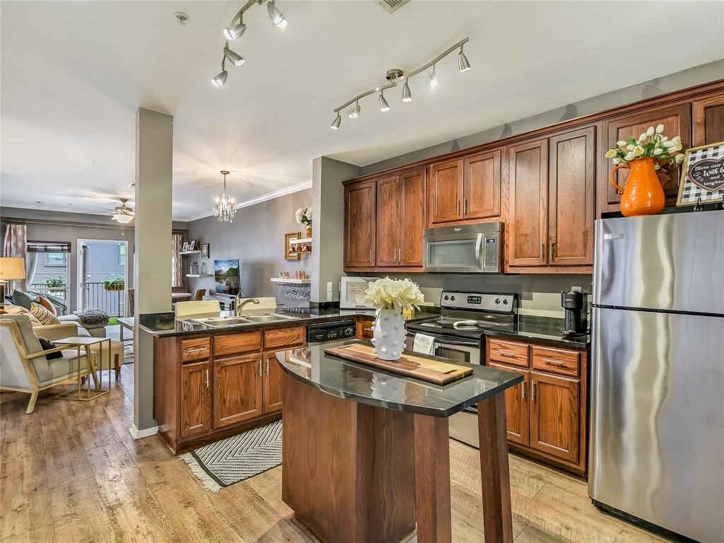 910 West 25th Street, Unit 404 Austin, TX 78705 - Photo 1 of 1 a kitchen with stainless steel appliances granite countertop a refrigerator a sink dishwasher a stove and white countertops with wooden floor