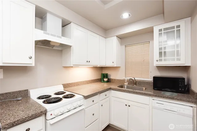 a kitchen with granite countertop a stove sink and cabinets