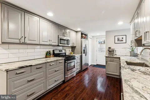 a kitchen with stainless steel appliances granite countertop a stove top oven a sink dishwasher a refrigerator and cabinets with wooden floor