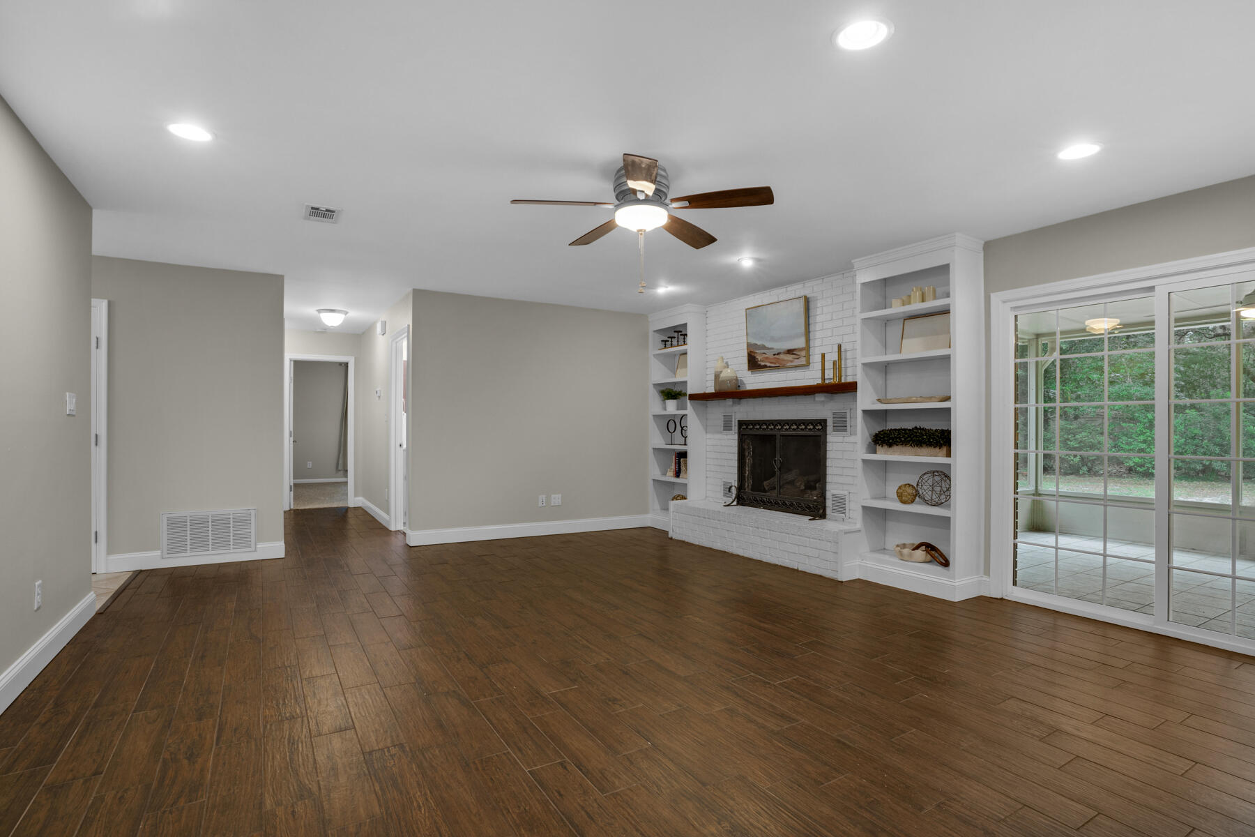 665 Brookhaven Way Niceville, FL 32578 - Photo 16 of 49 an empty room with wooden floor a ceiling fan a fireplace and windows