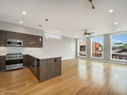 a large kitchen with stainless steel appliances wooden floor and a large window