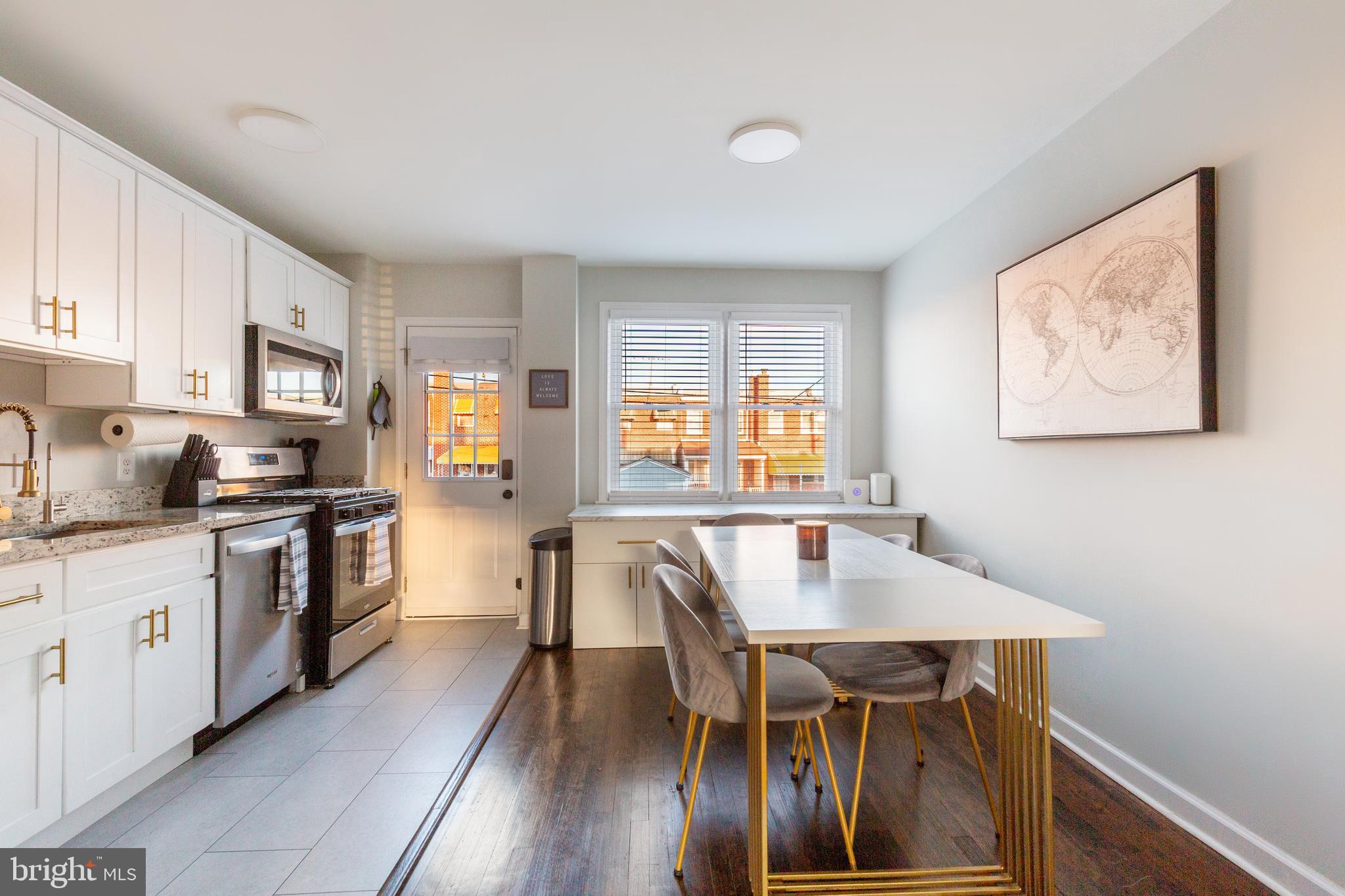 413 Imla Street Baltimore, MD 21224 - Photo 12 of 38 a kitchen with stainless steel appliances granite countertop a stove top oven a sink a refrigerator with a dining table and chairs