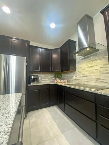 a large kitchen with kitchen island granite countertop a sink and cabinets