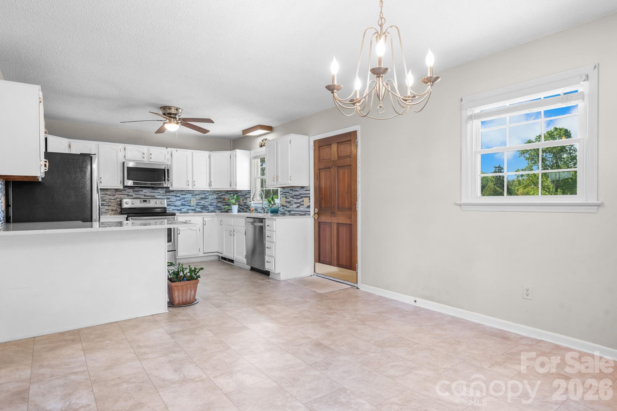65 Pinewood Road Granite Falls, NC 28630 - Photo 15 of 42 a kitchen with stainless steel appliances granite countertop a stove top oven a refrigerator a sink dishwasher a dining table and chairs with wooden floor