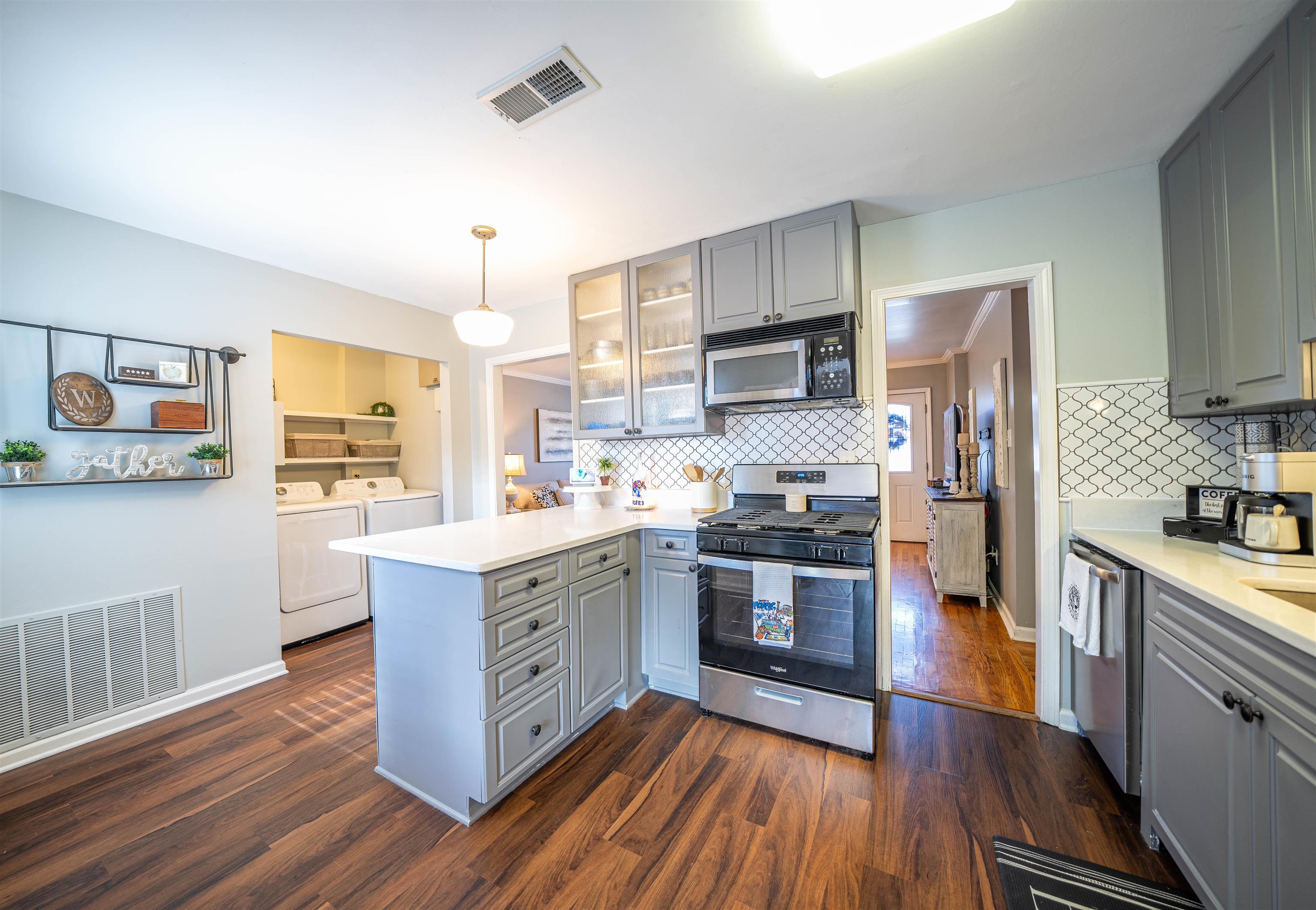 5163 Kaye Road Memphis, TN 38117 - Photo 8 of 23 Kitchen featuring washing machine and dryer, decorative light fixtures, stainless steel appliances, kitchen peninsula, and gray cabinetry