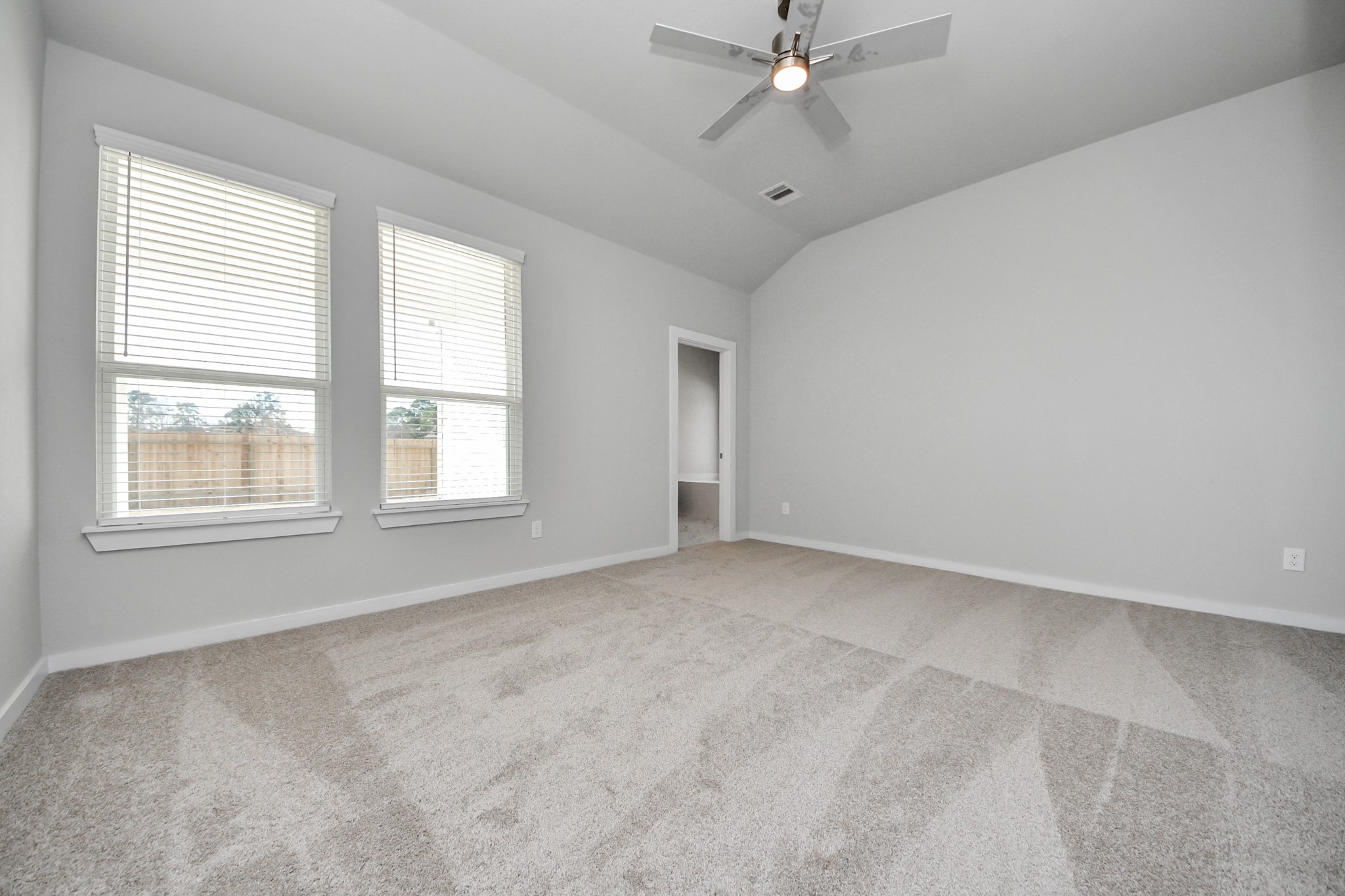 3002 Bury Park Dr Spring Spring, TX 77373 - Photo 23 of 45 Escape and relax in the exquisite primary suite, a haven to unwind after a long day. The spacious room, located on first floor, boasts plush carpeting, soothing paint tones, high ceilings, and expansive windows adorned with privacy blinds.