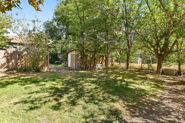 664 Wasatch Street Midvale, UT 84047 - Photo 26 of 33 Expansive lawn area, mature trees, wood fence, and a storage shed