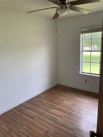 a view of an empty room with a window and wooden floor